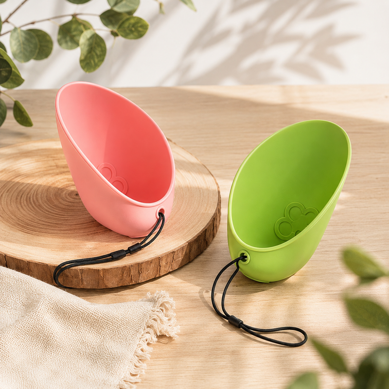 Pootr PawCap™ in roze en groen op houten ondergrond, draagbare hondendrinkbak